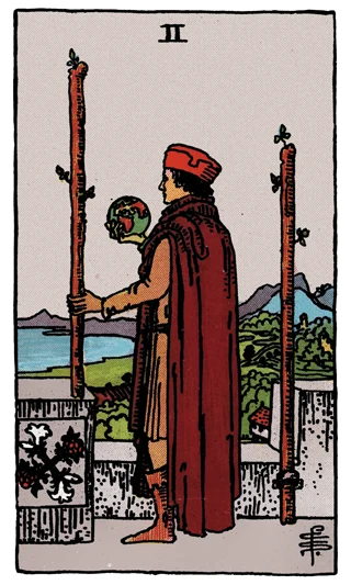 Two of Wands Rider-Waite-Smith tarot card showing a cloaked figure holding a globe and wand while looking across the sea.